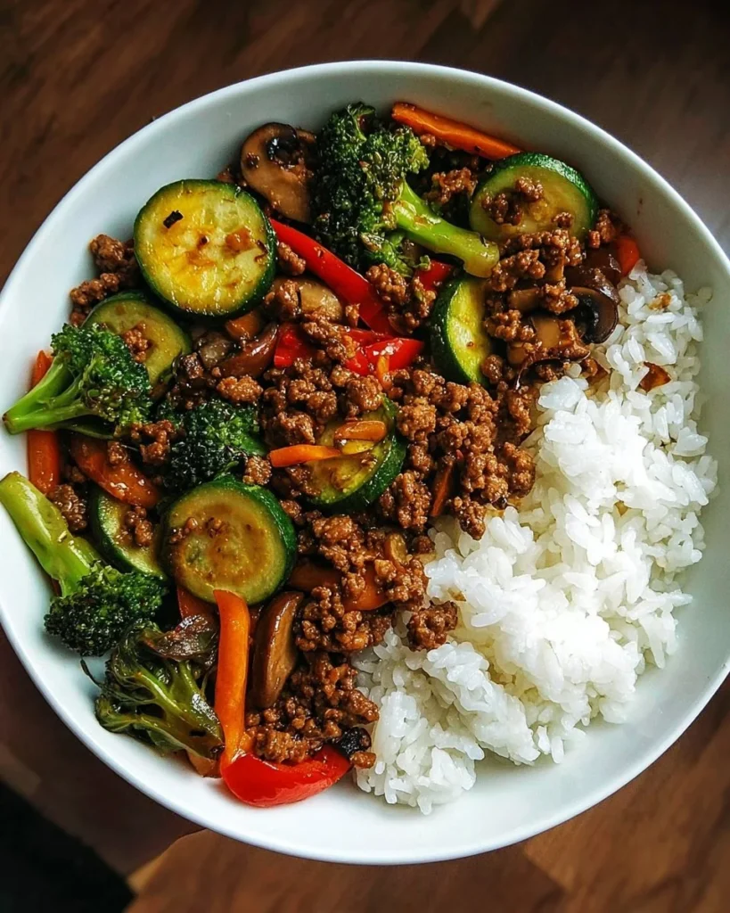 Spicy ground beef stir-fry bowl with garlic vegetables and rice